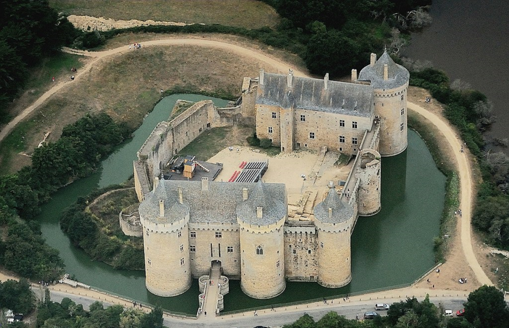 Picture of a castle with a tall walls, moat and internal buildings.
